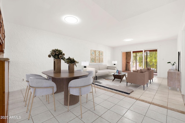 dining room featuring a textured wall and light tile patterned flooring