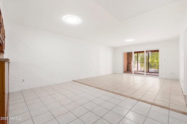 spare room with light tile patterned floors and a textured wall