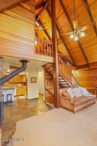 interior space with beam ceiling, high vaulted ceiling, a wood stove, and wood ceiling