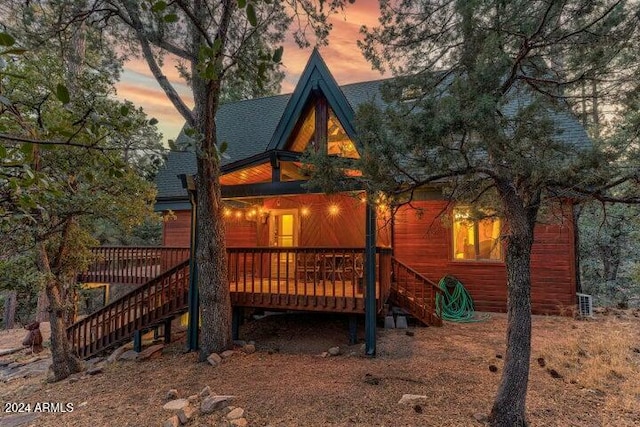 back house at dusk featuring a deck