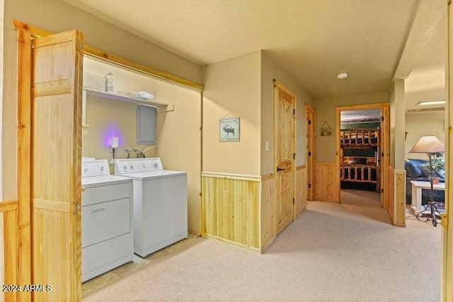 laundry area featuring separate washer and dryer, light colored carpet, and wood walls