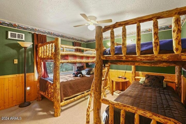 carpeted bedroom with ceiling fan, a textured ceiling, and wooden walls