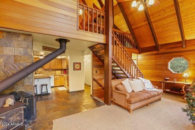 living room featuring wood ceiling, wooden walls, beam ceiling, high vaulted ceiling, and a wood stove