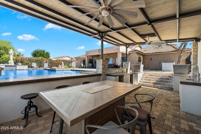 view of patio / terrace featuring a sink, area for grilling, a ceiling fan, and an outdoor pool
