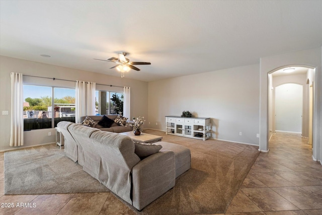 living area featuring arched walkways, ceiling fan, and baseboards