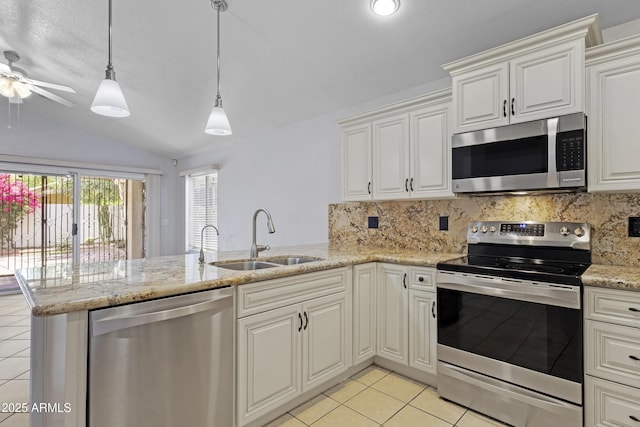 kitchen with vaulted ceiling, a sink, light tile patterned floors, a peninsula, and stainless steel appliances