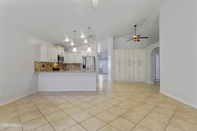 kitchen featuring stainless steel appliances, light stone countertops, a ceiling fan, and arched walkways