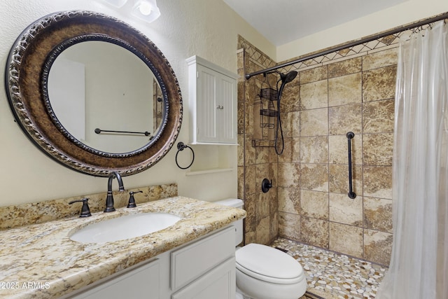 full bathroom with toilet, tiled shower, and vanity