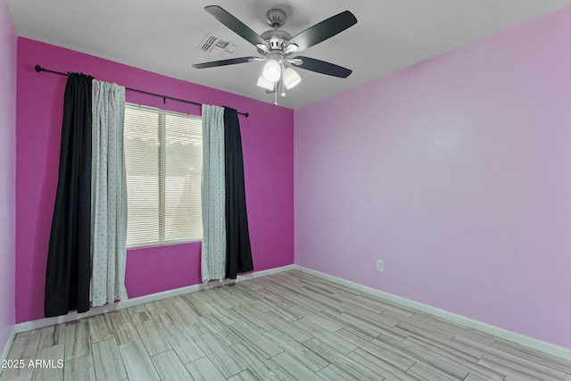 empty room with visible vents, a ceiling fan, baseboards, and wood finished floors