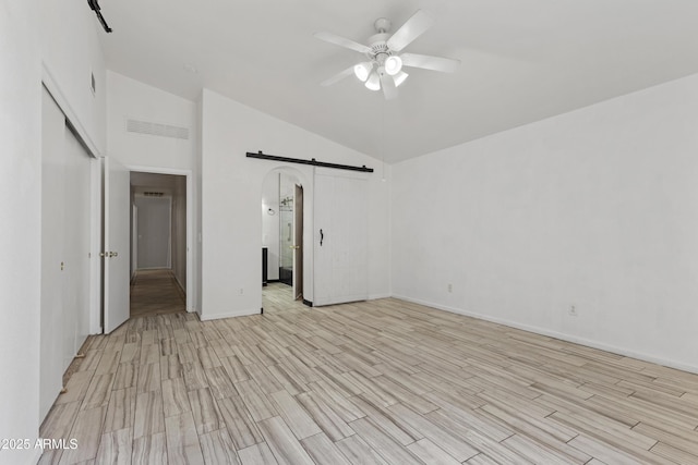 interior space featuring visible vents, ceiling fan, high vaulted ceiling, light wood-type flooring, and a barn door