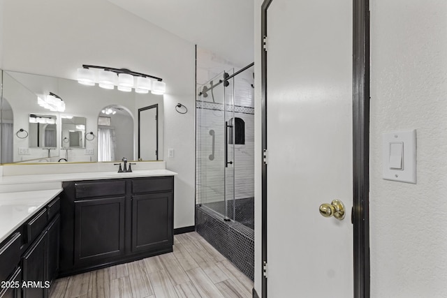 bathroom featuring a sink, two vanities, and a shower stall