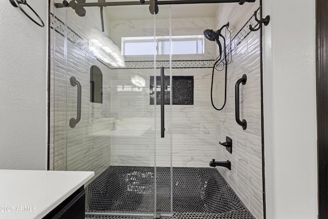 bathroom with vanity, a textured wall, and a stall shower