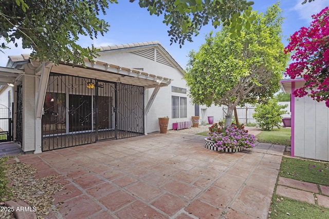 back of house with fence, a gate, a patio, and stucco siding