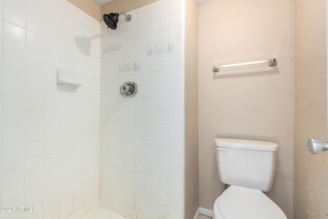 bathroom with a tile shower and toilet