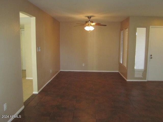 spare room with ceiling fan and dark tile patterned floors