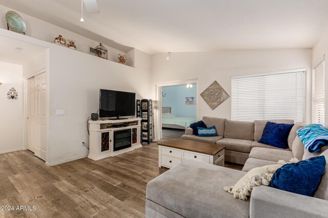 living room with ceiling fan, wood-type flooring, and vaulted ceiling