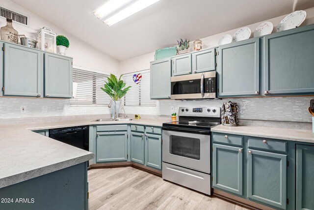 kitchen with light hardwood / wood-style flooring, backsplash, stainless steel appliances, sink, and lofted ceiling