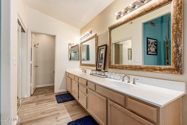 bathroom with lofted ceiling, hardwood / wood-style flooring, and vanity