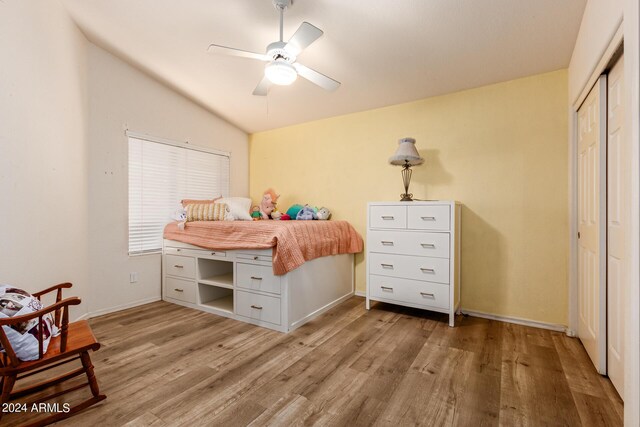 bedroom featuring ceiling fan, a closet, light wood-type flooring, and vaulted ceiling