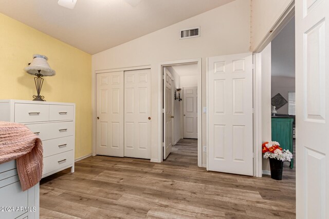 unfurnished bedroom with light wood-type flooring, lofted ceiling, ceiling fan, and a closet