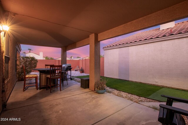 patio terrace at dusk featuring a yard