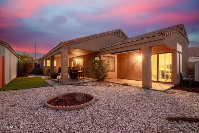 back house at dusk with a fire pit and a patio