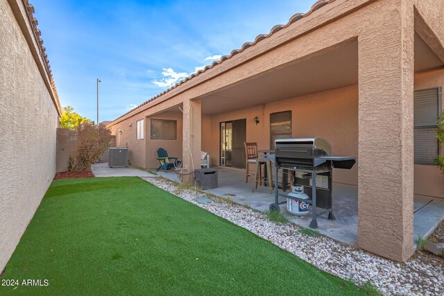 rear view of property featuring a yard, a patio area, and central air condition unit