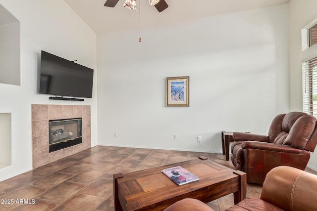 living room with ceiling fan, a high ceiling, a fireplace, and baseboards