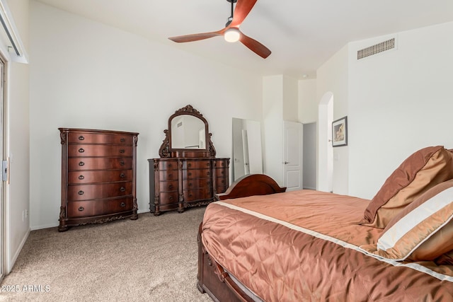 bedroom featuring arched walkways, light colored carpet, visible vents, a ceiling fan, and baseboards