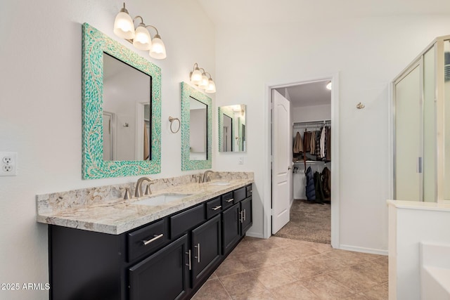 bathroom with double vanity, tile patterned flooring, a spacious closet, and a sink