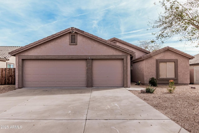 ranch-style house featuring an attached garage, fence, a tile roof, concrete driveway, and stucco siding