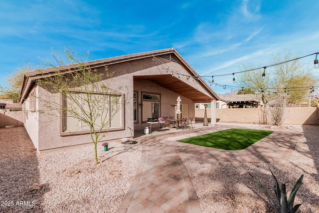 rear view of house with a patio, a fenced backyard, and stucco siding