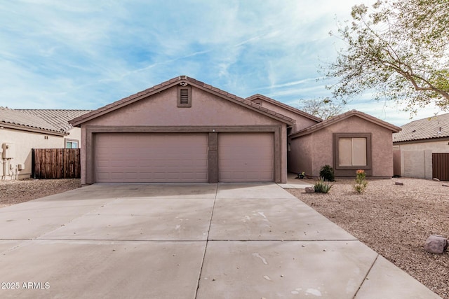 view of front facade featuring a garage, concrete driveway, fence, and stucco siding