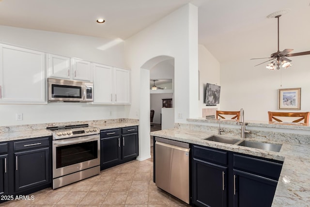 kitchen featuring ceiling fan, appliances with stainless steel finishes, vaulted ceiling, and a sink