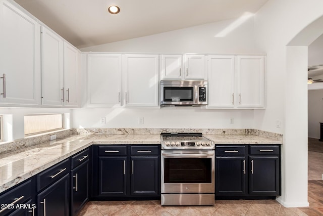 kitchen with arched walkways, lofted ceiling, light stone counters, stainless steel appliances, and white cabinetry