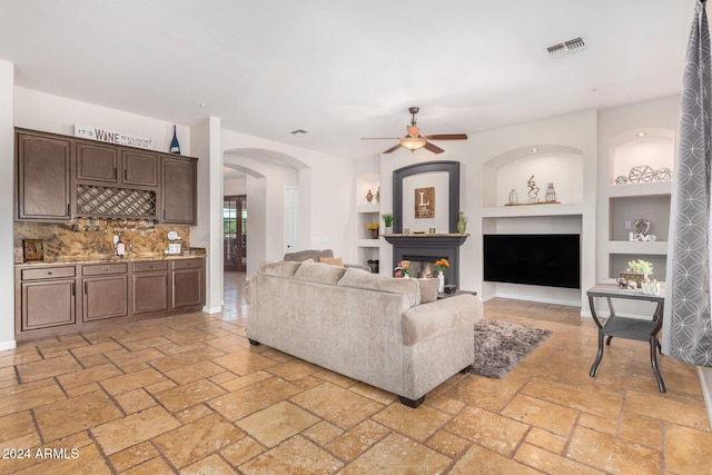 living room with built in shelves and ceiling fan