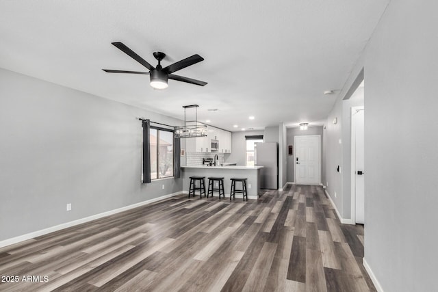 1180 W Rosal Ave, Apache Junction, AZ 85120 - unfurnished living room with dark wood-style flooring, baseboards, a ceiling fan, a sink, and recessed lighting