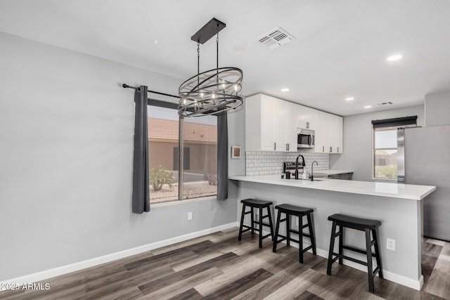 1180 W Rosal Ave, Apache Junction, AZ 85120 - kitchen featuring appliances with stainless steel finishes, a chandelier, dark wood-style flooring, light countertops, and a kitchen bar