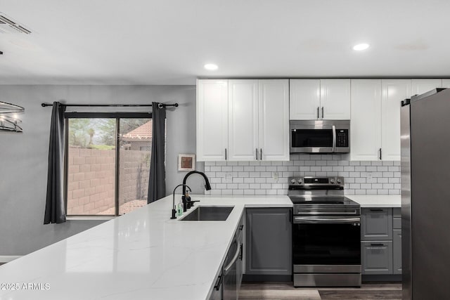 1180 W Rosal Ave, Apache Junction, AZ 85120 - kitchen with appliances with stainless steel finishes, a sink, gray cabinets, dark wood-type flooring, and backsplash
