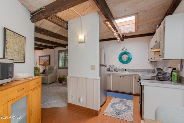 6840 E 2nd St Unit 23, Scottsdale, AZ 85251 - kitchen with appliances with stainless steel finishes, a sink, wood ceiling with exposed beams, light wood-style flooring, and light countertops