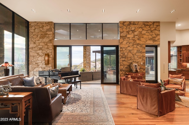 living room featuring sink, light wood-type flooring, and a towering ceiling