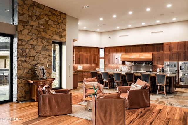 living room featuring a healthy amount of sunlight, a towering ceiling, and light wood-type flooring