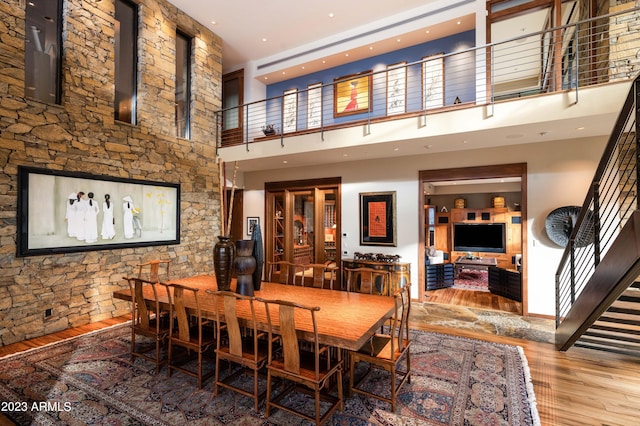 dining space with a towering ceiling and hardwood / wood-style flooring