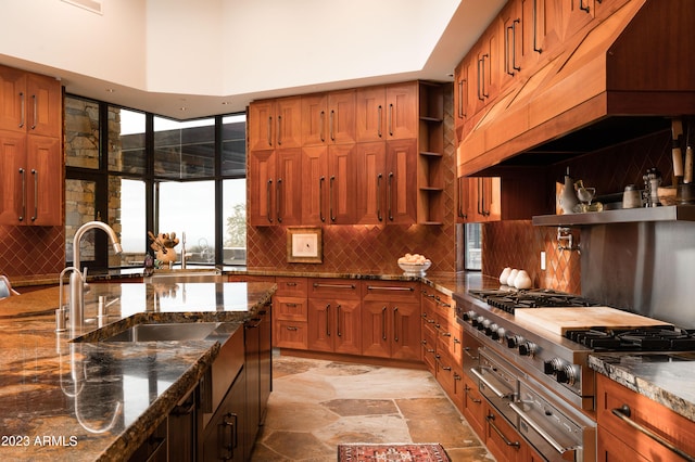 kitchen with gas stovetop, sink, light tile floors, tasteful backsplash, and dark stone countertops