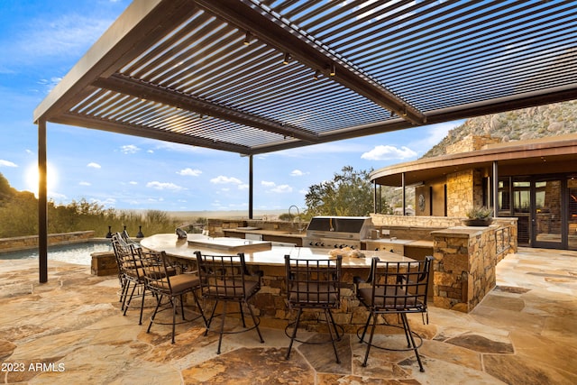 view of terrace featuring area for grilling, a pergola, a bar, and an outdoor kitchen