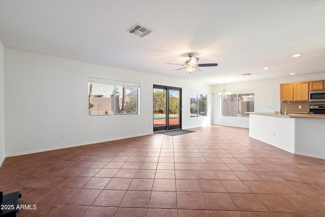 unfurnished living room featuring ceiling fan with notable chandelier, light tile patterned floors, and sink