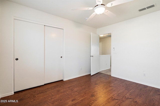 unfurnished bedroom with dark hardwood / wood-style flooring, ceiling fan, and a closet