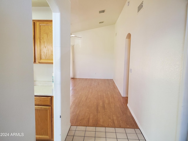 hallway with lofted ceiling and light tile patterned floors