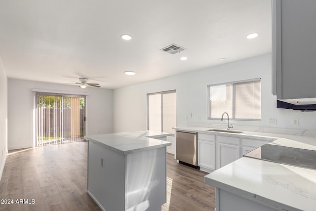 kitchen with stainless steel dishwasher, sink, light hardwood / wood-style flooring, a center island, and white cabinetry