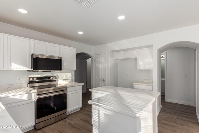 kitchen with dark hardwood / wood-style floors, a kitchen island, white cabinetry, and stainless steel appliances